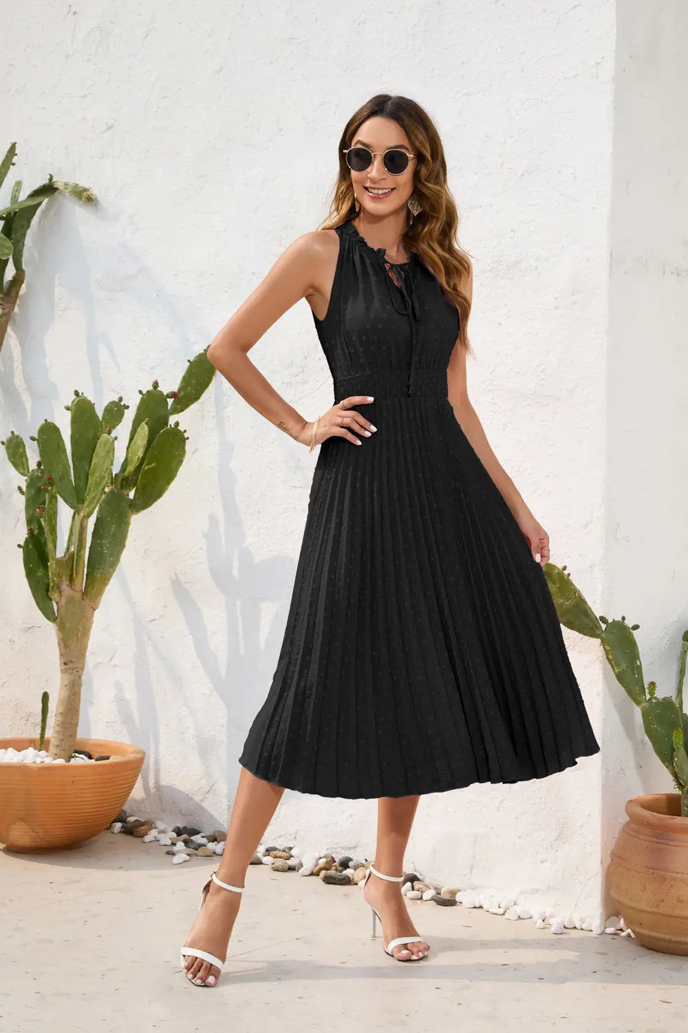 Woman in a black dress standing outdoors with cacti in the background