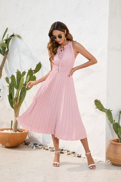 Woman in a pink dress standing in front of a white wall with cacti.