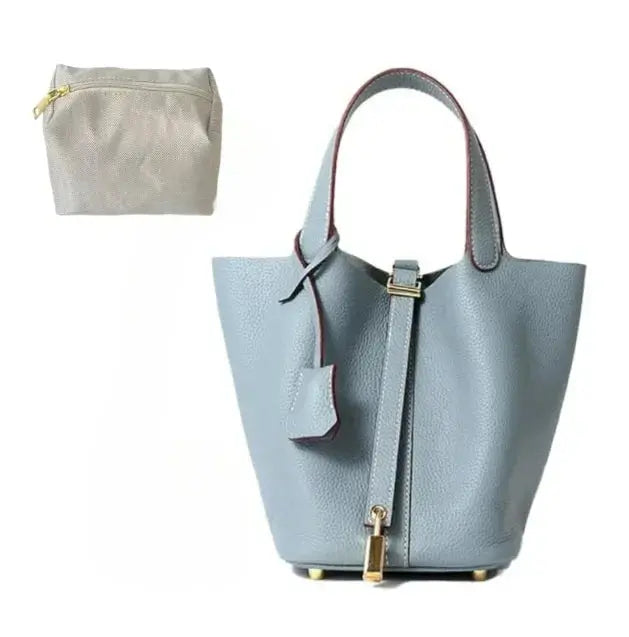 Light blue handbag with gold accents and a matching pouch on a white background