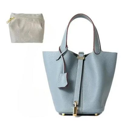 Light blue handbag with gold accents and a matching pouch on a white background
