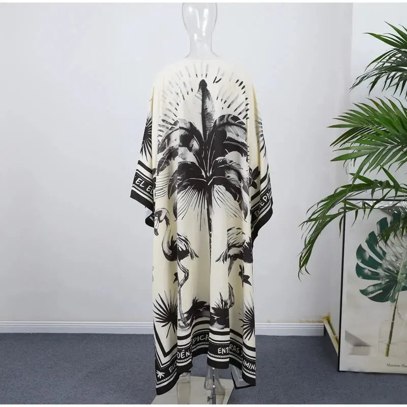 Black and white palm leaf patterned kimono on a mannequin against a white wall with a plant in the corner.