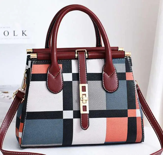 women's handbag Checkered handbag with brown handles and strap on a light background